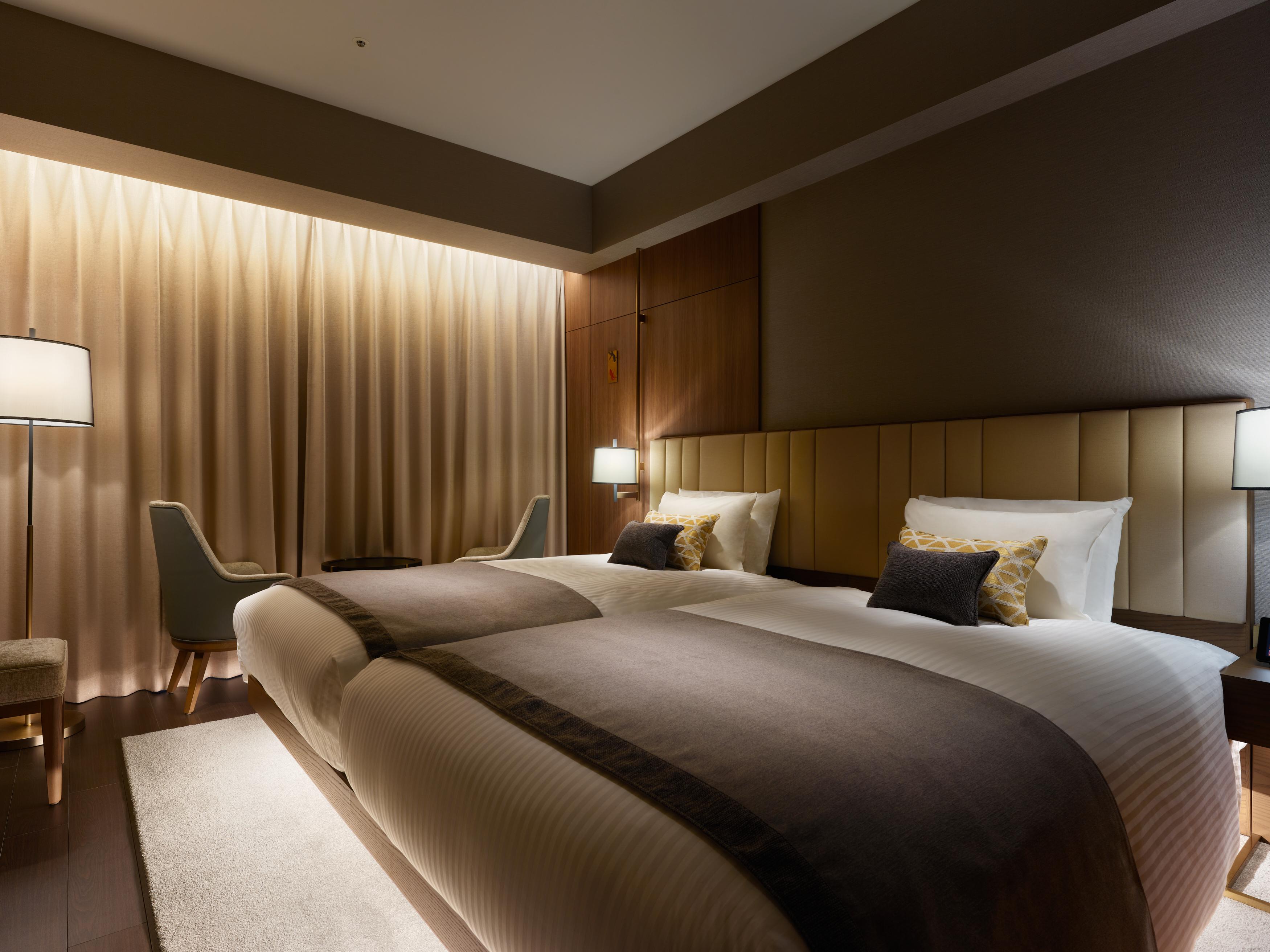 Mitsui Garden Hotel Roppongi Tokyo Premier Kültér fotó The photo shows a modern hotel room featuring two twin beds with elegant bedding. The room is adorned with soft, neutral tones and has a warm ambiance created by subtle lighting. A pair of bedside lamps provide additional light, and there is a cozy c